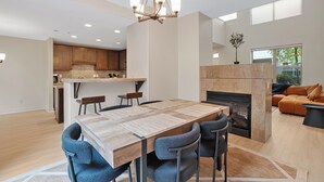 Un vaste espace de vie comprenant une table à manger, des chaises, une cheminée et une cuisine en arrière-plan.