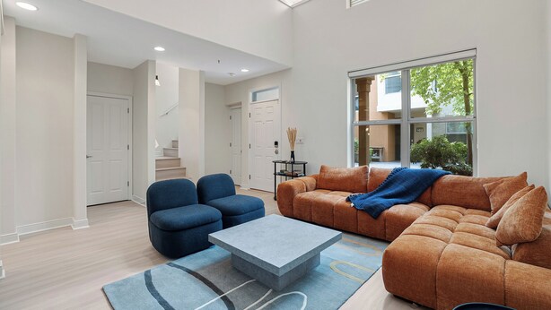 Un salon spacieux avec une grande fenêtre, un canapé, deux fauteuils et une table basse.