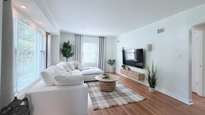 Un salon moderne avec un canapé d’angle, une table basse et un téléviseur à écran plat.