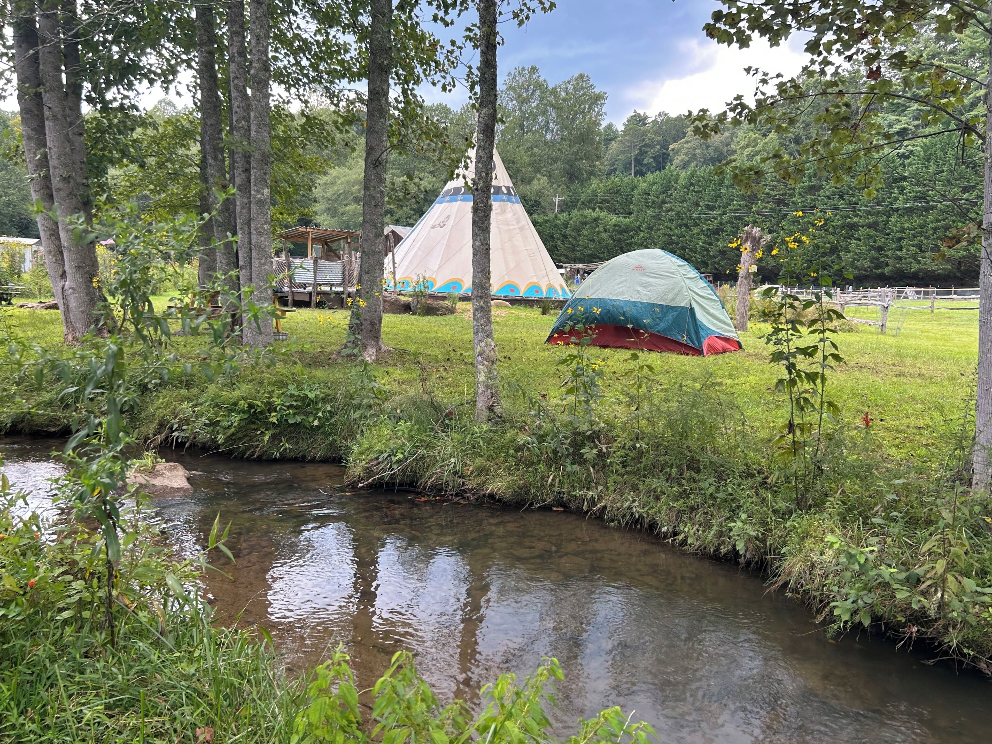 Een camping met tenten en een beekje.
