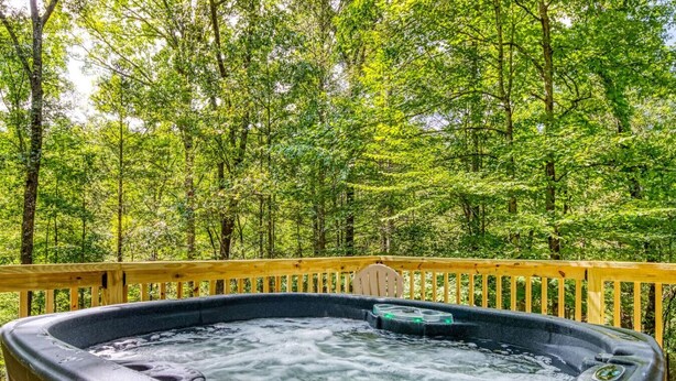 Un bain à remous sur une terrasse en bois, entouré d’une forêt.