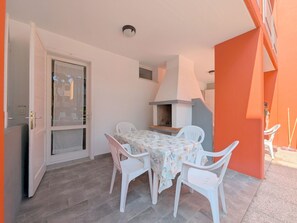 Une terrasse avec une table et des chaises, un barbecue et une porte donnant sur un balcon.