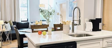 Une cuisine moderne équipée d’un lave-vaisselle, de meubles blancs et d’un coin repas avec une table et des chaises.