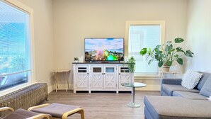 A living room with a television, seating, and a plant. - Light filled apt in Historic Home by UW & Downtown (Seattle)
