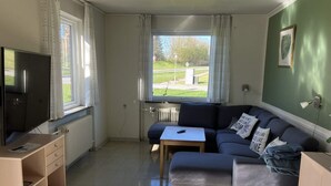 Ett vardagsrum med en TV, en soffa, ett litet bord och ett skåp.