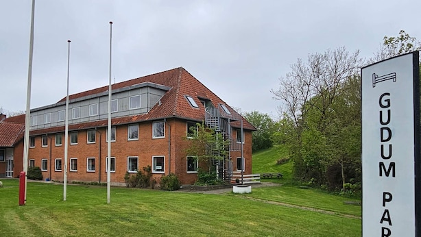 En byggnad med en skylt som visar texten ”GUDUM PARK” och en gräsyta framför.