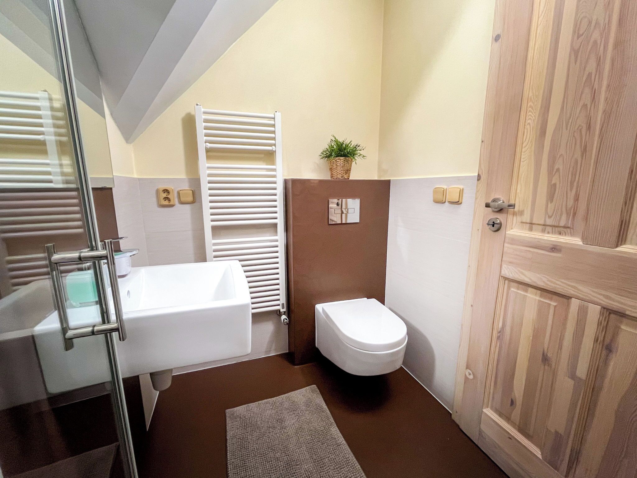 Ein Badezimmer mit einer Badewanne, Toilette und einer Holztür.