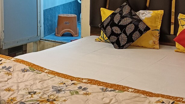 Une chambre à coucher avec un lit, une tête de lit, une armoire et un mur décoré d’un motif.