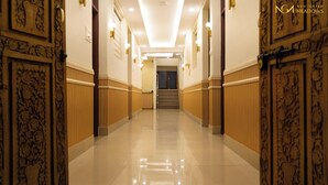 Un pasillo de hotel con paneles de madera, suelo pulido y una escalera que lleva a una habitación oscura.
