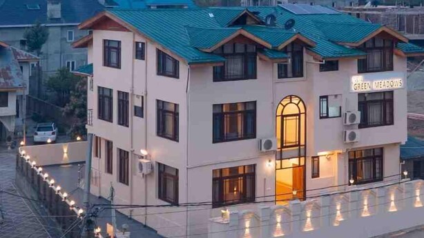 Um hotel chamado "Green Meadows", com uma entrada notável e uma fileira de luzes ao longo do caminho.