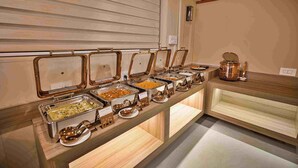 Buffet com várias estações de comida, cada uma com um recipiente identificado.