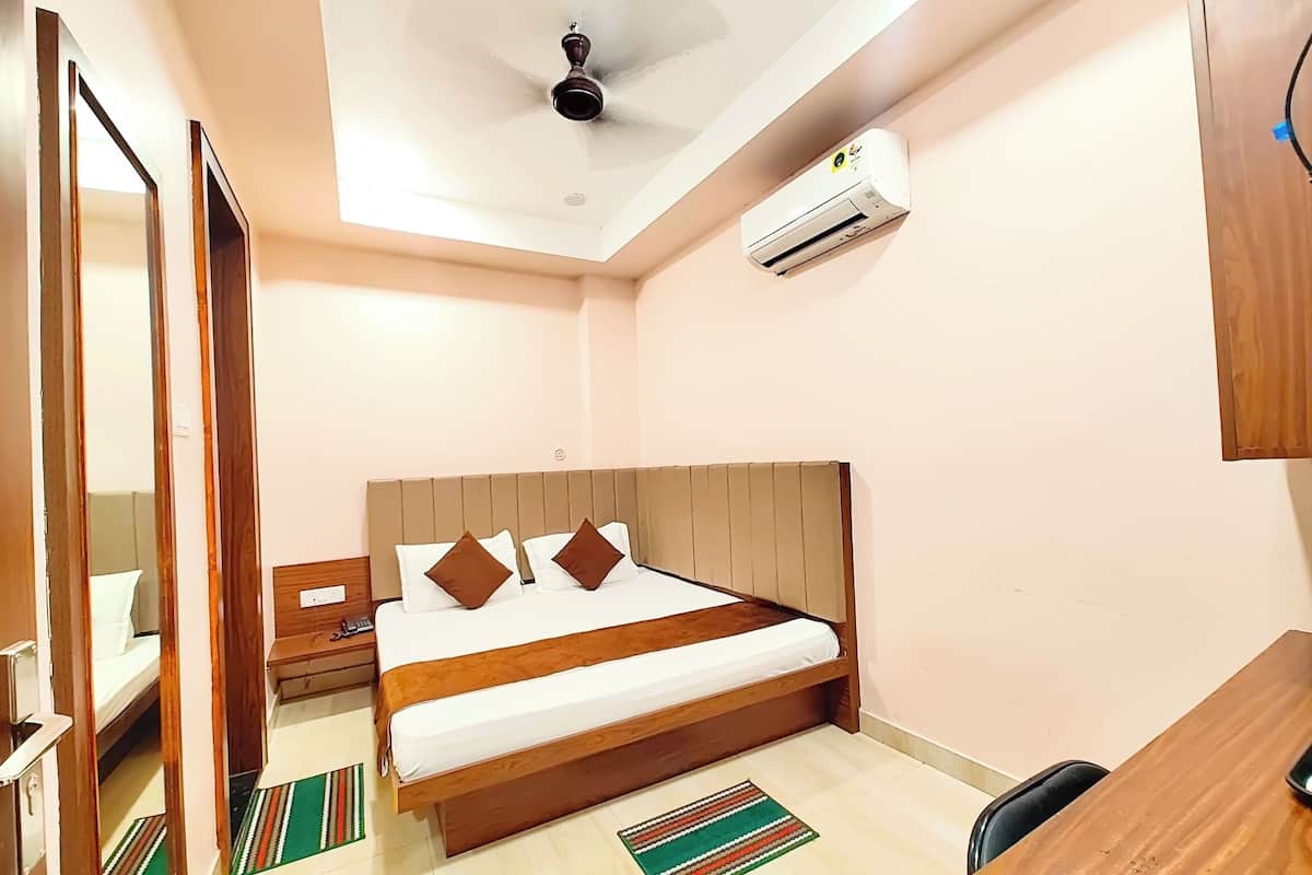 Un dormitorio con cama de madera, ventilador de techo, equipo de aire acondicionado, escritorio y espejo.