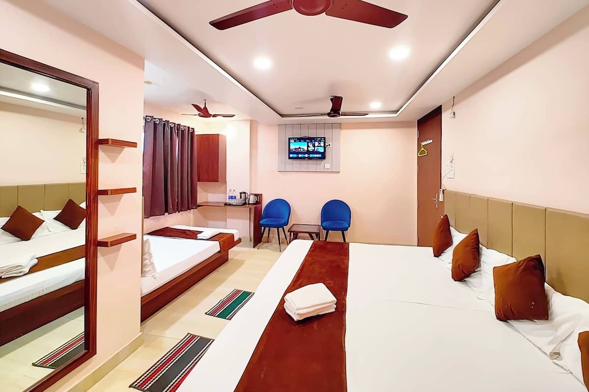 Habitación de hotel con dos camas, un escritorio, un televisor y un ventilador de techo.