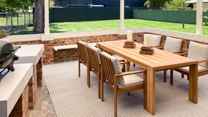 Un patio al aire libre con chimenea de ladrillo, una mesa de madera y sillas.