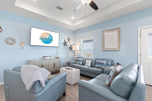 A living room with a light blue sofa, a white coffee table, and a ceiling fan.