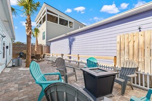 A patio with outdoor seating, a fire pit, and a wooden fence.