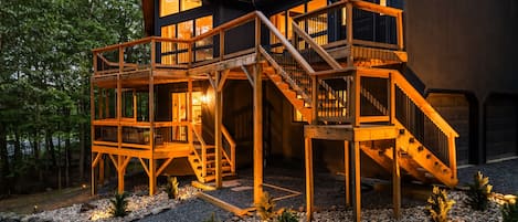 A modern wooden cabin with multiple decks and a staircase leading to the main entrance.