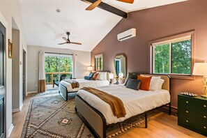 A bedroom with two beds, a ceiling fan, a large window, and a view of trees. - Pocono Speak Easy Hot Tub Golf Simulator 1920 Bar (East Stroudsburg)
