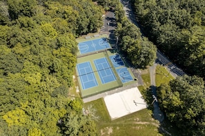 An aerial view of a tennis court surrounded by dense forest.