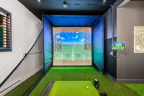 A golf training room with a digital screen displaying a golf course layout, a practice mat, and a golf ball. - Pocono Speak Easy Hot Tub Golf Simulator 1920 Bar (East Stroudsburg)