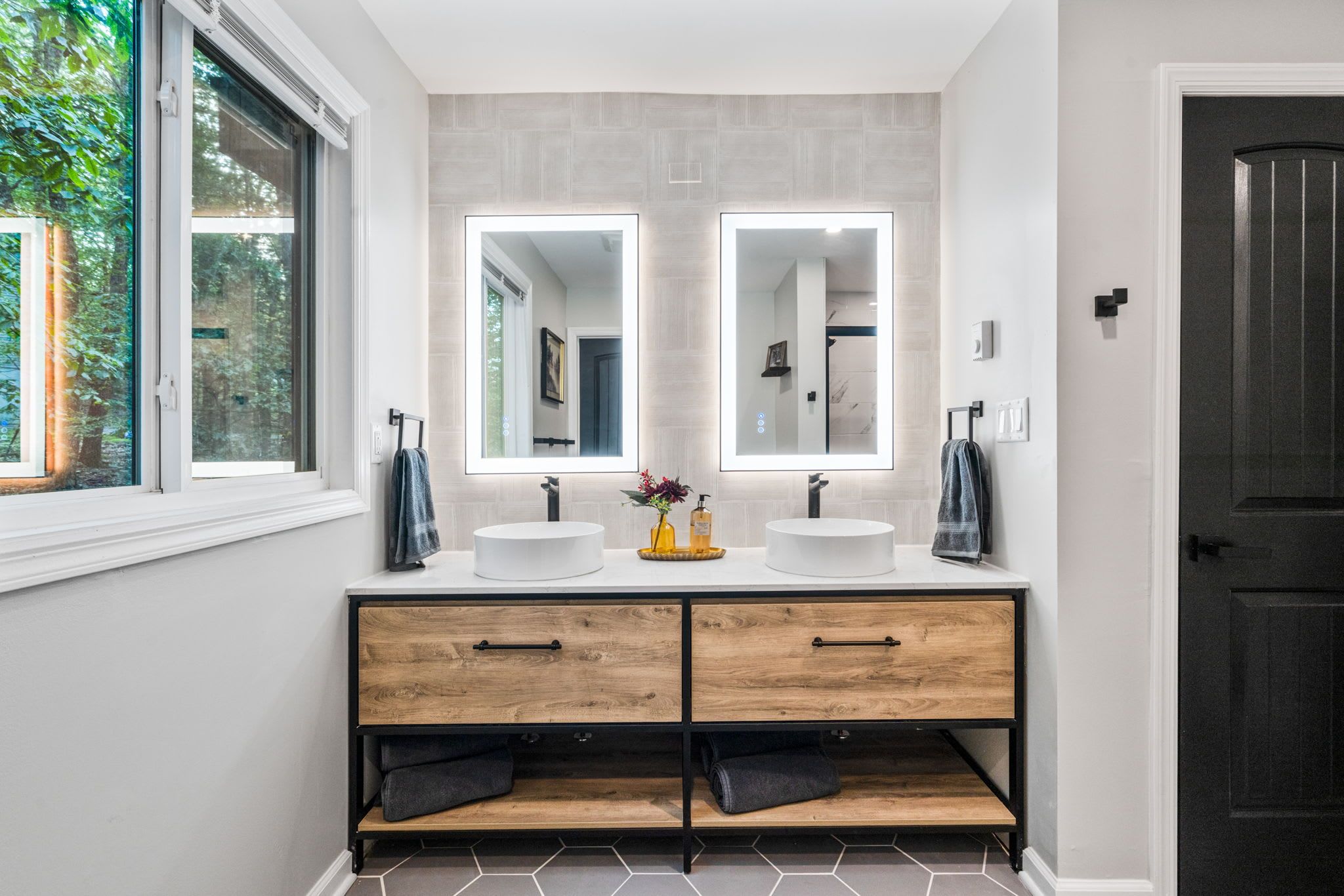 Een moderne badkamer met twee wastafels, een houten wastafelmeubel en grote spiegels.