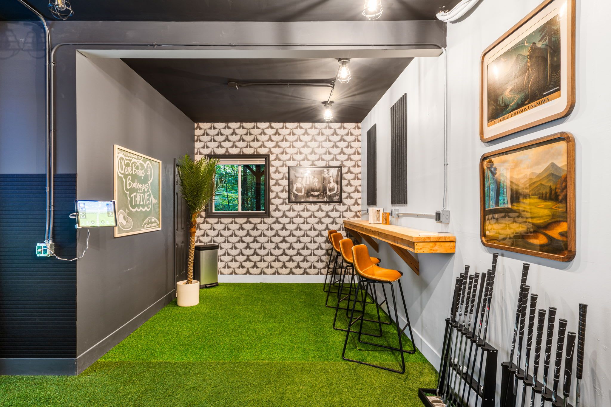 Un interior modern amb zona de bar, gespa artificial verda i quadres als murs.