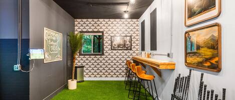 A modern interior with a bar area, green artificial grass, and framed artwork on the walls.