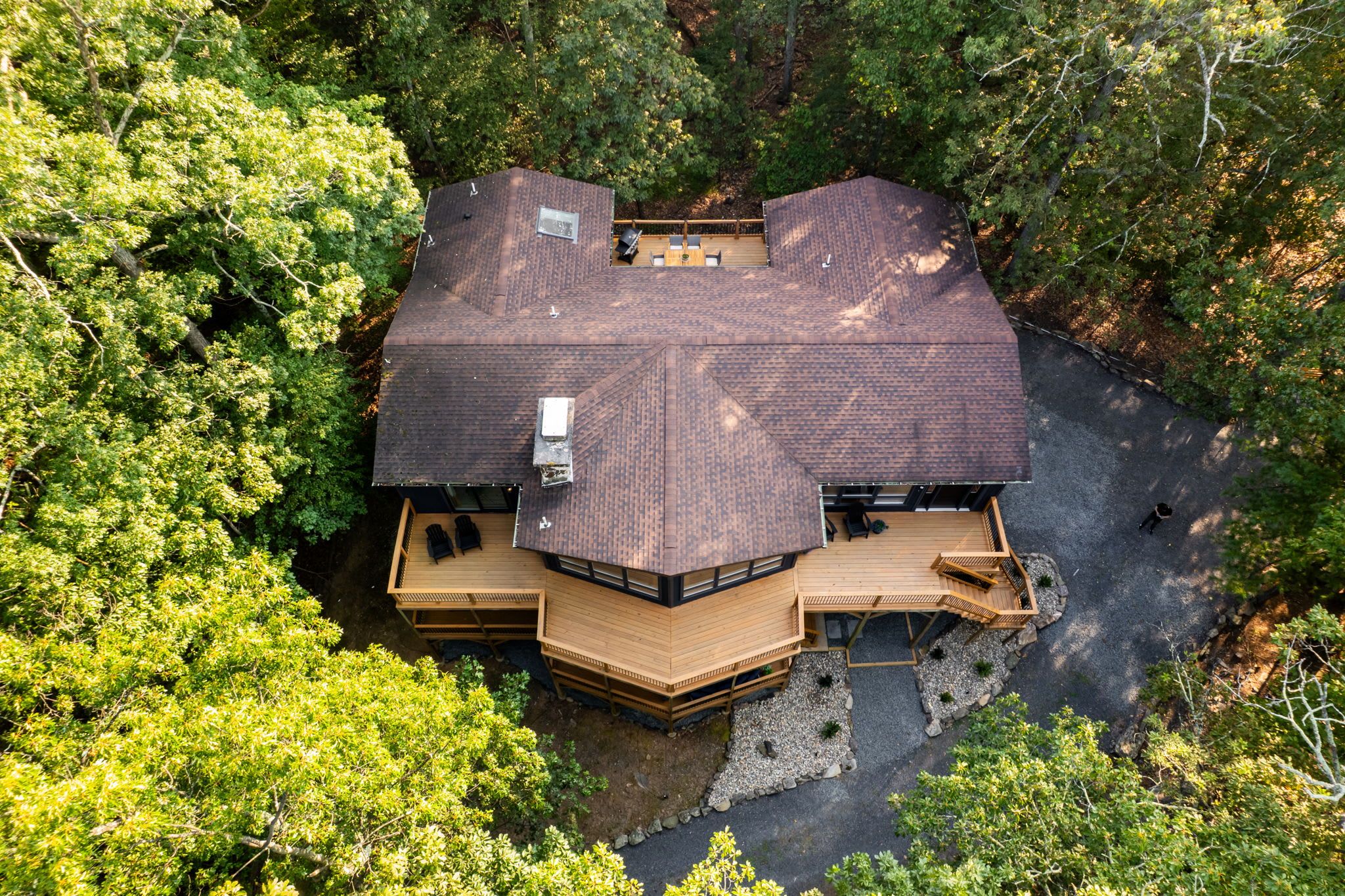 A large, multi-level wooden house surrounded by dense trees.