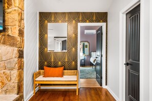 A hallway with a stone wall, a bench with an orange cushion, and a patterned wall. - Pocono Speak Easy Hot Tub Golf Simulator 1920 Bar (East Stroudsburg)
