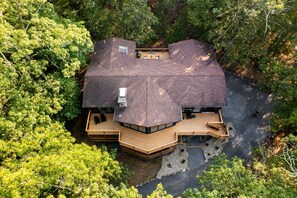 Une grande maison en bois à plusieurs niveaux, entourée d’une forêt dense.