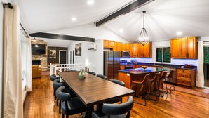 A spacious kitchen with wooden cabinets, a central island, and a dining area with a long table and chairs.