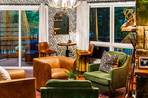 A cozy living room with leather sofas, a green armchair, and a fireplace. - Pocono Speak Easy Hot Tub Golf Simulator 1920 Bar (East Stroudsburg)