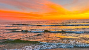 Une plage avec des vagues et un coucher de soleil.
