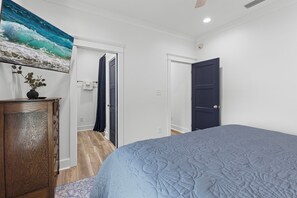 A bedroom with a bed, a dresser, a painting, and a door.