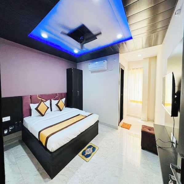A modern hotel room with a large bed, a ceiling fan, and a flat-screen TV. - Hotel Imperial Inn Varanasi (Varanasi)