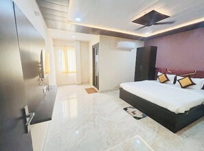 A bedroom with a bed, a wardrobe, a television, and an air conditioning unit. - Hotel Imperial Inn Varanasi (Varanasi)
