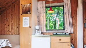 A compact room with a bed, a kitchenette with a coffee maker, a window with curtains, and a wooden ceiling. - 4 Person Holiday Park Home in Grindsted (Grindsted)
