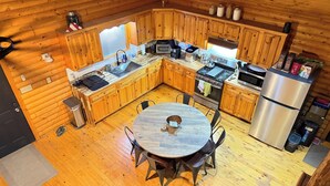 Una cocina compacta con muebles de madera, un refrigerador de acero inoxidable y un comedor con una mesa redonda y sillas.