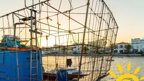 A boat with a net enclosure, a blue structure, and the name 'TAVIRA' on its side. - Urbaniza o da Pegada Apartamento T2 (Tavira)