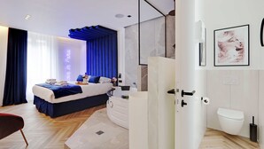 A modern bedroom with a bed, bedside table, and a bathroom with a toilet and sink. - Suberb Suite With Jacuzzi Le Marais Beaubourg (Paris)