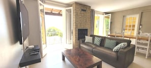 Uma sala de estar com sofá, mesa de centro, televisão e lareira.
