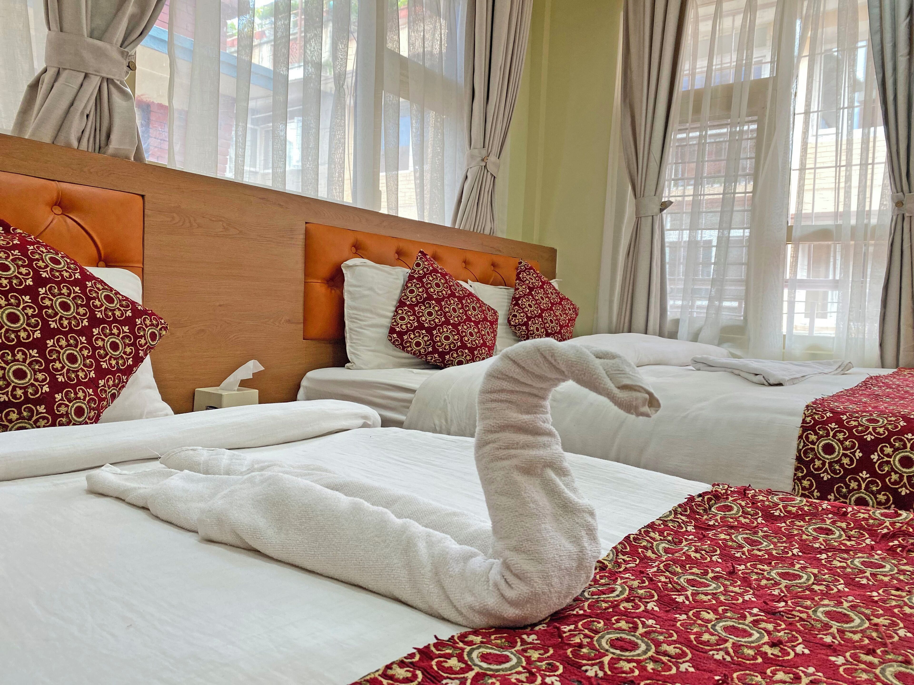 Habitació d'hotel amb dos llits, cada un amb roba de llit blanca i coixins vermells amb dibuixos.