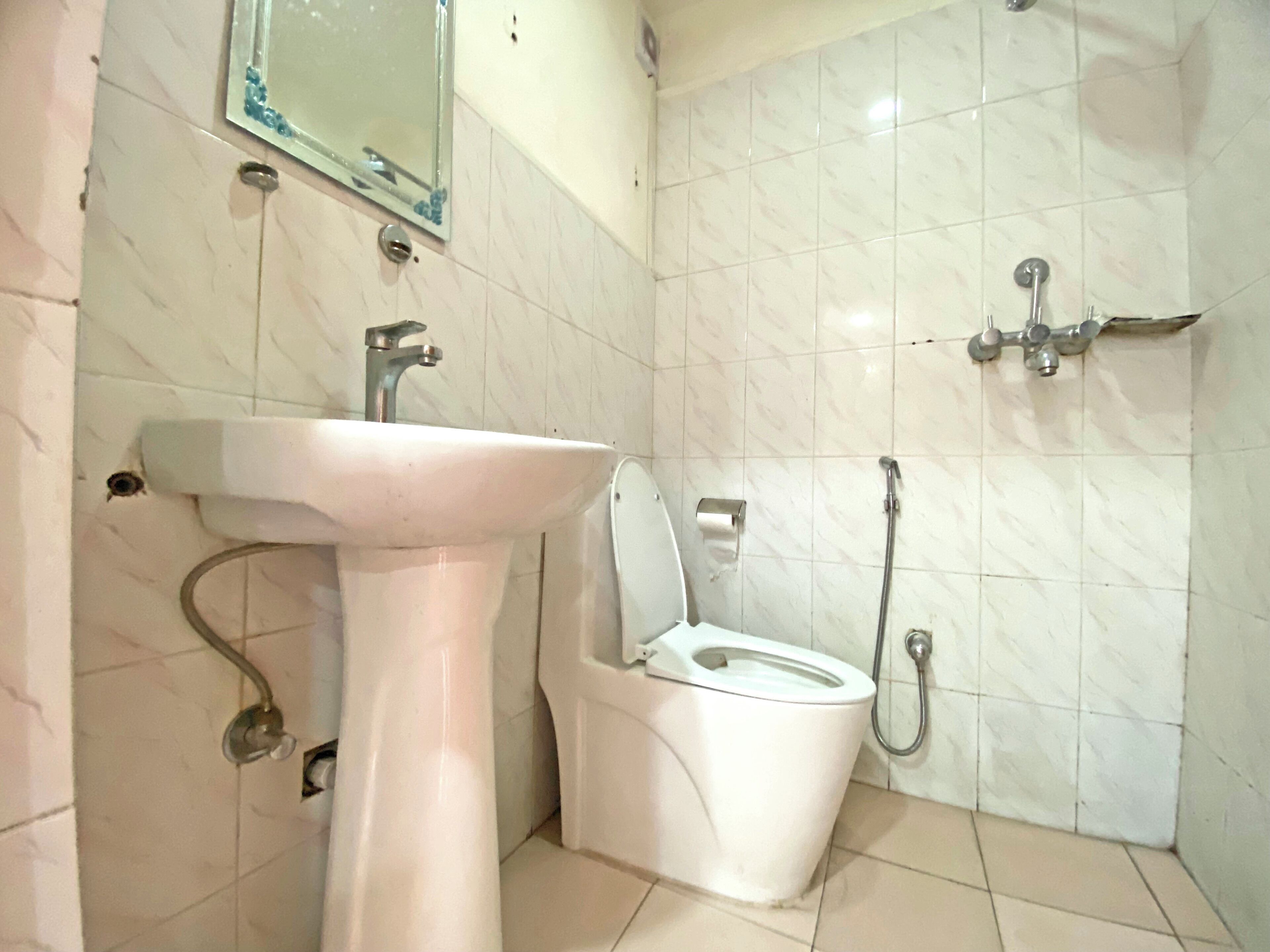 A bathroom with a pedestal sink, a toilet, and a shower.