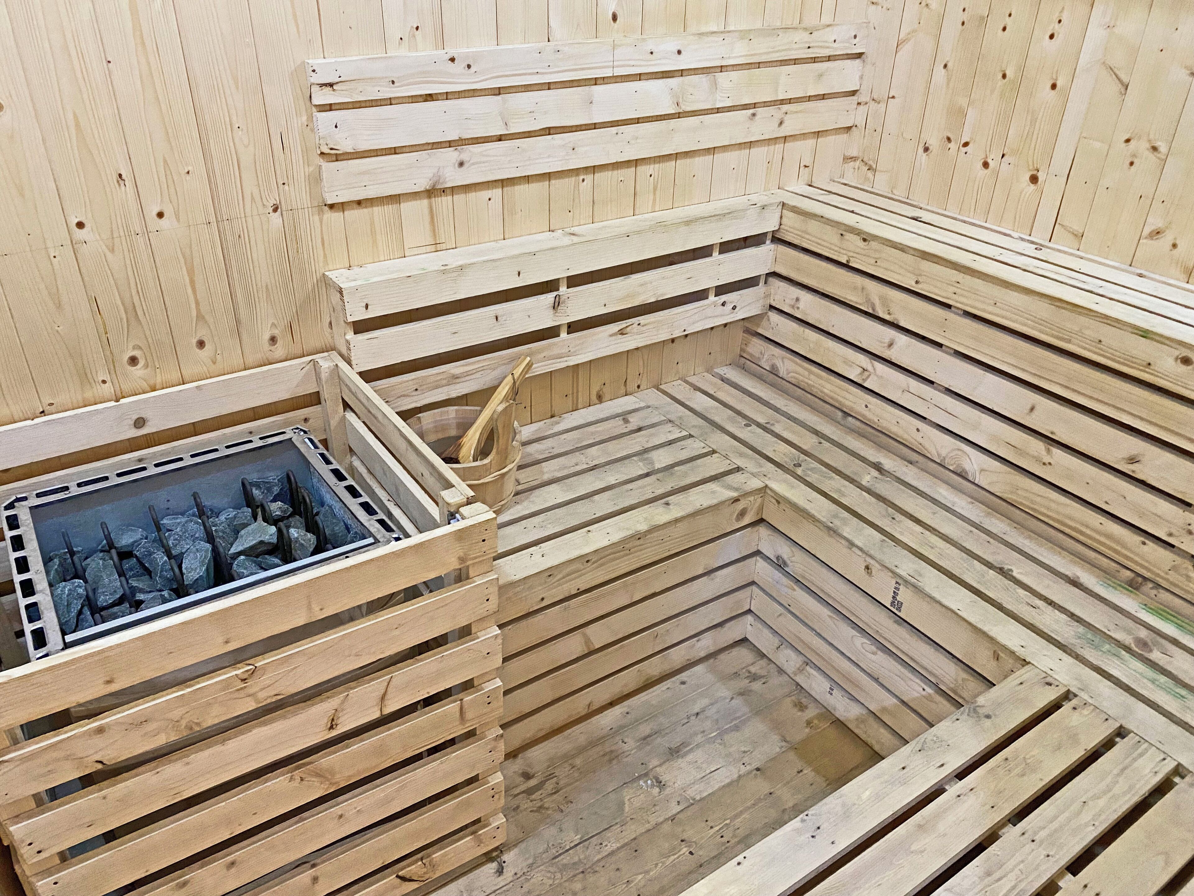 A sauna with wooden benches and a stone basin.