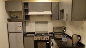 A compact kitchen with a refrigerator, stove, oven, and washing machine.