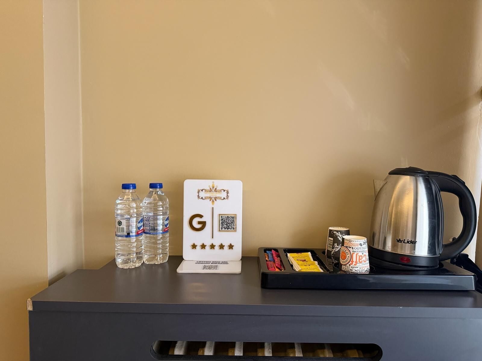 A minibar setup with bottled water, a coffee maker, and a tray with snacks.