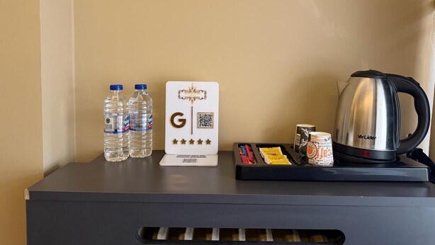 A minibar setup with bottled water, a coffee maker, and a tray with snacks. - SUITES NECATİBEY (Ankara)