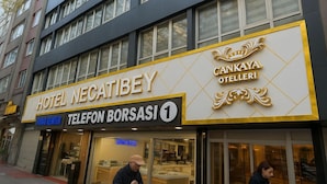 Hotel Necatibey con un cartel de Cankaya Otelleri y un teléfono público visible.