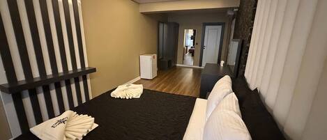 Una habitación de hotel con una cama, un refrigerador blanco pequeño y un espejo en la pared.