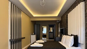 Una habitación de hotel moderna con una cama grande, una mesita de noche, un tocador y un baño visible a través de una puerta abierta.